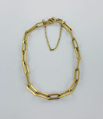 gros plan d'un bracelet en chaîne en or sur une surface blanche