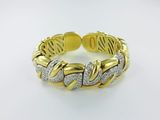 a close up of a gold and diamond bracelet on a white surface