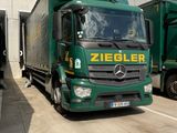 two green trucks parked next to each other in front of a building