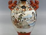 a vase with a painting on it sitting on a table