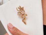 the woman is wearing a white shirt and a gold broochle