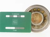 a green credit card sitting next to a silver coin