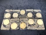 six different types of gold coins in plastic containers on a black surface