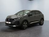 Une voiture grise est garée dans une grande pièce au sol noir.