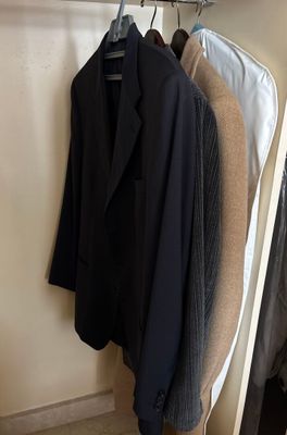 three jackets hanging on a clothes rack in a closet