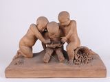 sculpture représentant trois enfants jouant avec un oiseau, posée sur un socle en bois