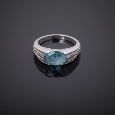Gros plan sur une bague ornée d'une pierre bleue sur un fond noir