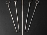 four pairs of scissors and a needle on a black surface