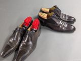 pair of men ' s black leather shoes with red soles on a grey surface