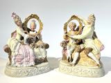 deux figurines représentant un couple assis sur une chaise avec un chien