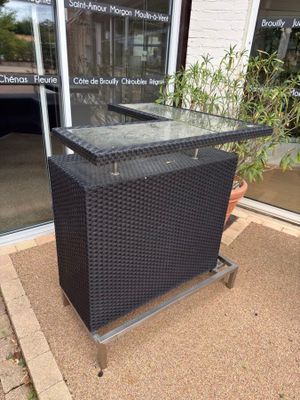 a black wicker bar with a glass top in front of a building