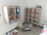 a room with bookshelves, a desk, and other items on the floor
