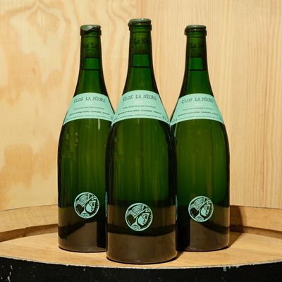 three bottles of wine sitting on top of a wooden barrel