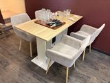 a wooden table with four chairs and a tray with wine glasses on it