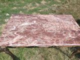 une table avec un plateau en marbre, montée sur roulettes, posée dans l'herbe