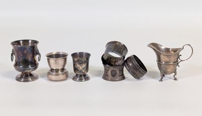 cinq tasses en argent et une cruche posées sur un plateau blanc