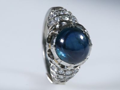 gros plan d'une bague avec une pierre bleue entourée de diamants