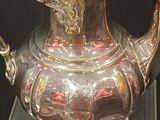 a silver tea pot on display in a glass case