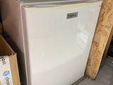 un petit réfrigérateur blanc dans le coin d'une pièce