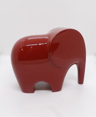 une figurine d'éléphant rouge posée sur une surface blanche
