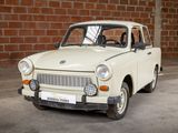a small white car parked in front of a brick wall