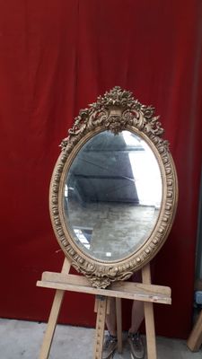 un miroir posé sur un socle en bois devant un rideau rouge