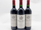 trois bouteilles de vin rouge posées sur une table blanche