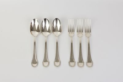 four forks and two spoons on a white surface