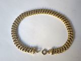 a close up of a gold chain bracelet on a white surface