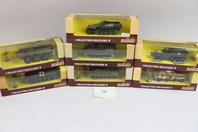 trois modèles réduits de véhicules militaires dans leurs boîtes, posés sur une surface blanche