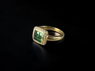 a close up of a ring with a green stone surrounded by diamonds