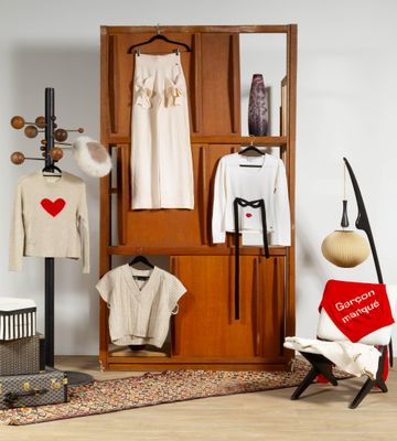une armoire avec des vêtements suspendus à des cintres et une chaise placée devant