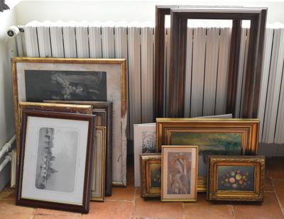 many framed pictures on the floor next to a radiator