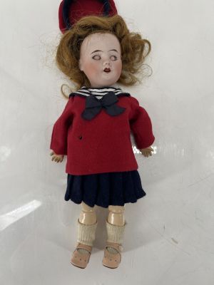 une poupée qui porte un pull rouge et une jupe bleue
