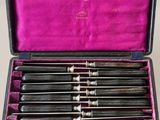 an old set of six knives in a case on a table