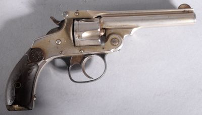 Un vieux pistolet est posé sur une table devant un fond blanc.