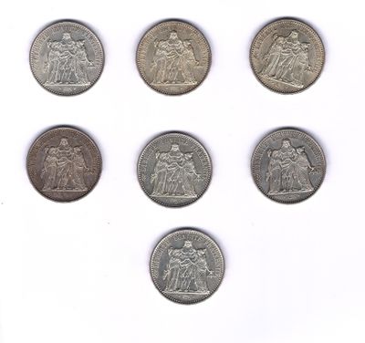 six types différents de pièces d'argent sur une surface blanche