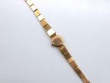 a close up of a gold watch on a white surface
