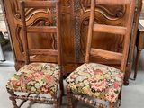 deux chaises en bois aux assises rembourrées de motifs floraux, placées devant une grande porte en bois