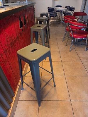 des tables et des tabourets dans un restaurant aux murs rouges et au sol carrelé