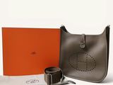 une boîte orange avec une ceinture et un sac gris avec une boucle argentée
