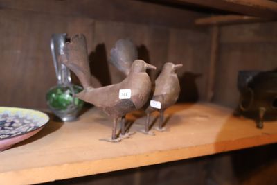 trois oiseaux posés sur une étagère à côté d'une assiette