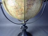 a large globe on a stand on a gray background