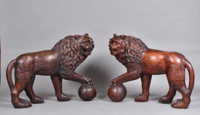 pair of carved wooden lions with ball on feet