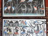 two paintings of birds and people on a wall in a room