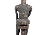 an old wooden statue of a man sitting on a stool