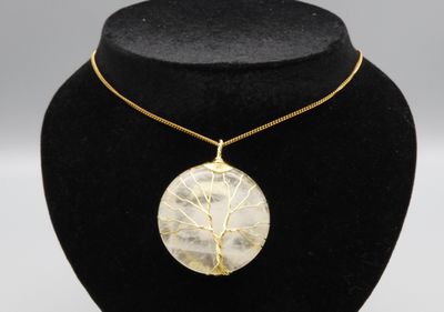 un collier plaqué or avec un pendentif représentant l'arbre de vie, présenté sur un mannequin noir