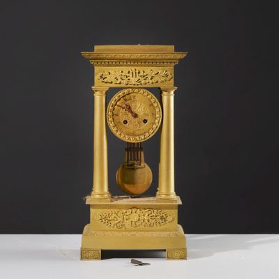 une horloge en or posée sur une table blanche