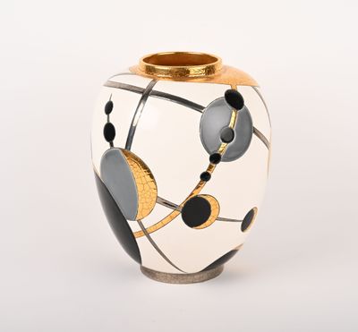 un vase blanc orné de motifs noirs et dorés