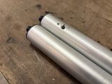 two metal tubes that are sitting on a wooden table